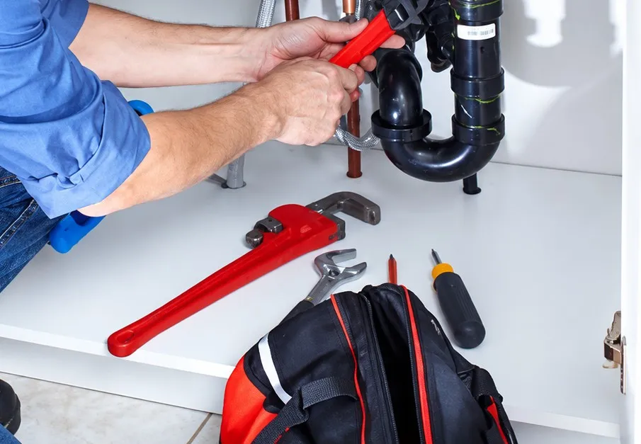 Fontanero reparando el sifón bajo un fregadero